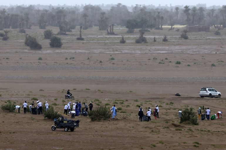 Volunteers, including tourists, pick up waste as they take part in a desert cleaning campaign during the Nomads Festival in Mhamid El-Ghizlane in Morocco's southern Sahara desert on April 12, 2025. It may be the gateway to the vast Sahara desert, but that doesn't mean it's free of that modern scourge of the environment: the rubbish humanity discards. (Photo by Abdel Majid BZIOUAT / AFP)