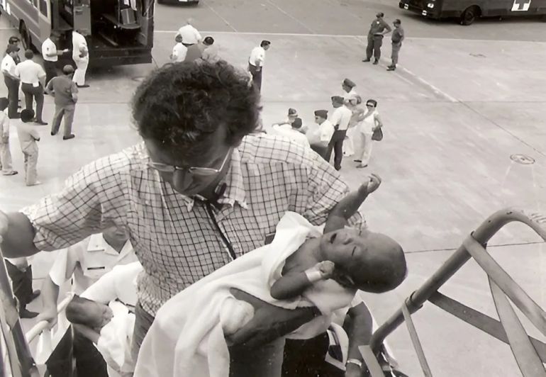 Frederick Burkle carries an infant on board an evacuation plane [Courtesy Frederick Burkle]