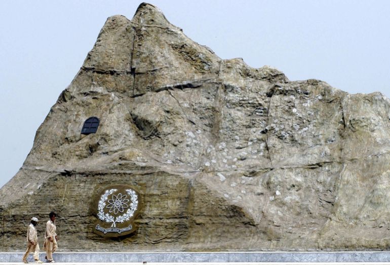 Two Pakistani labourers walk past the replica of the Chagi mountain, where Pakistan held its first ever nuclear test, in Islamabad, 01 July 2004. President Pervez Musharraf said Pakistan will conduct an