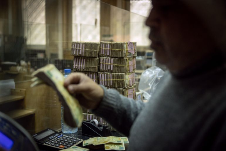 DAMASCUS, SYRIA - DECEMBER 24: An employee works in front of stacks of Syrian pounds at the exchange department at the Central Bank Of Syria on December 24, 2024 in Damascus, Syria. On December 8, rebel forces in Syria retook the capital and several other cities from longtime ruler Bashar al-Assad, who fled the country for Moscow. The fall of the Assad regime marks a new chapter for Syria, which has been mired in a multi-party civil war since 2011, sparked by the Arab Spring uprisings. (Photo by Chris McGrath/Getty Images)