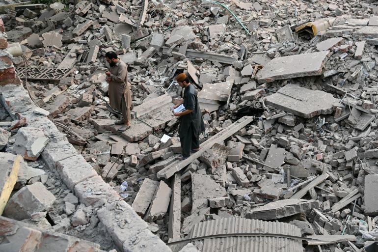 Locals stand on the debris of destroyed structures at the Government Health and Educational complex in Muridke about 30 kilometres from Lahore, on May 7, 2025, after Indian strikes. The death toll from Indian strikes on Pakistan has increased to eight, the country's military spokesman said on May 7, as India fired missiles at Pakistani territory and Islamabad vowed to