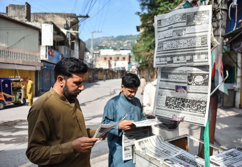 Residents read morning Urdu newspapers with the headline 'The ceasefire between Pakistan and India' on a roadside in Muzaffarabad, the capital of Pakistan-administered Kashmir, on May 11, 2025.