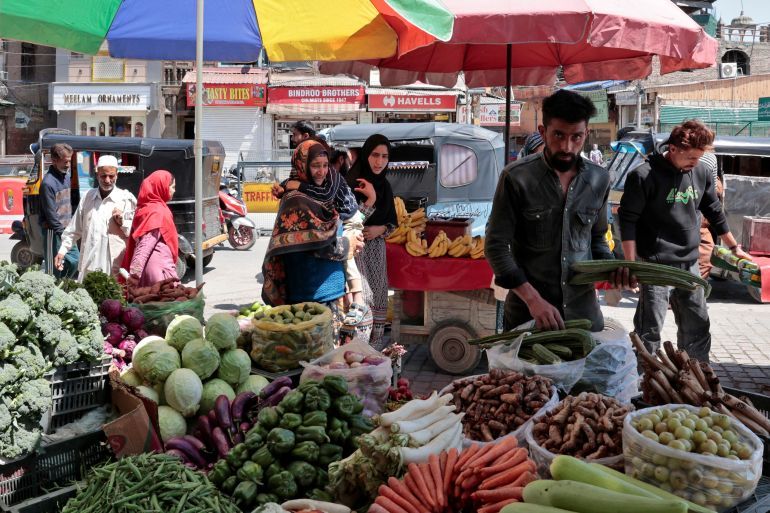 People walk as vendors arrange vegetables on a roadside stall in Srinagar, Indian Kashmir, May 12, 2025. REUTERS/Sharafat Ali
