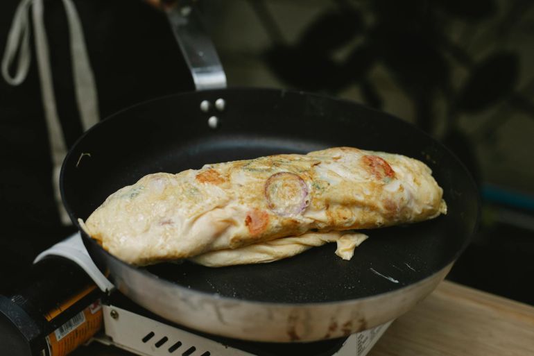 Appetizing egg roll frying on pan