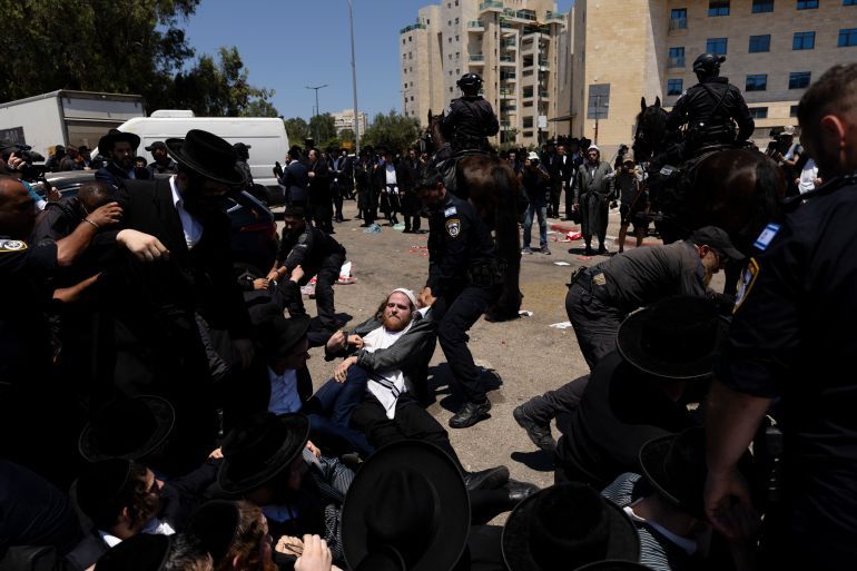 RAMAT GAN, ISRAEL - AUGUST 5: Ultra-Orthodox Jewish men clash with police officers during a demonstration against drafting to the Israeli military near a recruitment base on August 5, 2024 in the Tel HaShomer area of Ramat Gan, Israel. Hundreds of Ultra-Orthodox men who were previously exempted from military service were due to arrive at the recruitment office here today, following a Supreme Court ruling that ended the exemption for yeshiva students. (Photo by Amir Levy/Getty Images)
