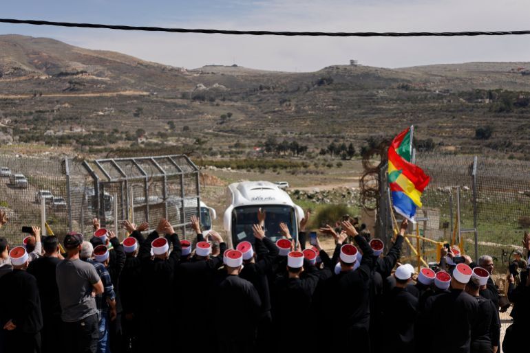 Druze men gather near a border barrier in the village of Majdal Shams, in the Israeli-annexed Golan Heights, as buses transporting visiting Druze men from Syria approach in the Syrian side of the Golan, on March 14, 2025. A delegation of Syrian Druze clerics is planning to visit a pilgrimage site in Israel on March 14, for the first time since Israel's creation in 1948, a source close to the group said. (Photo by John Wessels / AFP)