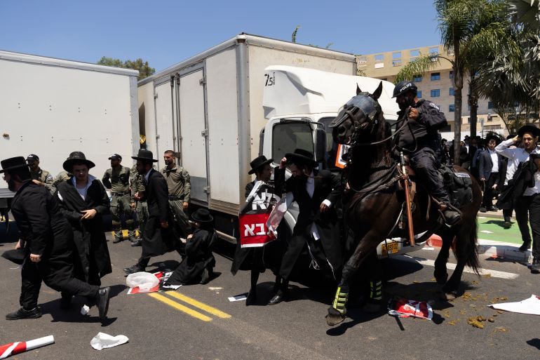 RAMAT GAN, ISRAEL - AUGUST 5: Ultra-Orthodox Jewish men clash with mounted police officers during a demonstration against drafting to the Israeli military near a recruitment base on August 5, 2024 in the Tel HaShomer area of Ramat Gan, Israel. Hundreds of Ultra-Orthodox men who were previously exempted from military service were due to arrive at the recruitment office here today, following a Supreme Court ruling that ended the exemption for yeshiva students. (Photo by Amir Levy/Getty Images)
