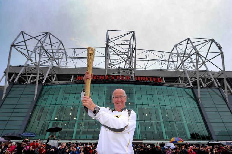 MANCHESTER, UNITED KINGDOM - JUNE 24: In this handout image provided by LOCOG, Torchbearer 005 Sir Bobby Charlton holds the Olympic Flame outside Old Trafford football stadium on the Torch Relay leg between Salford and Moss Side on Day 37 of the London 2012 Olympic Torch Relay on June 24, 2012 in Manchester, England. The Olympic Flame is now on day 37 of a 70-day relay involving 8,000 torchbearers covering 8,000 miles. (Photo by LOCOG via Getty Images)