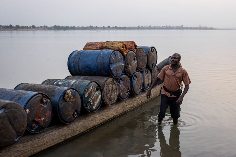 A man stands next to a pirogue full of empty barrels headed for the Democratic Republic of Congo (DRC) to collect palm oil in Bangui, on February 27, 2025. (Photo by PATRICK MEINHARDT / AFP)