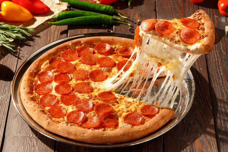 American pizza with pepperoni, mozzarella and tomato sauce. Pizza on a wooden table, morning, dawn.; Shutterstock ID 697347319; purchase_order: aj; job: ; client: ; other: