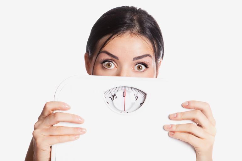 beautiful young scared woman holding scales, isolated against white background; Shutterstock ID 78297394; purchase_order: aj; job: ; client: ; other:
