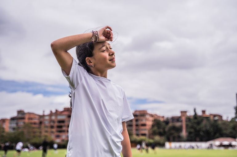 Child girl wiping the sweat from the forehead after a match on the sports field