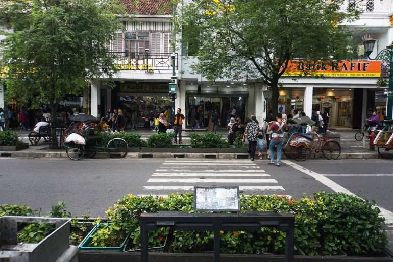 Yogyakarta, Indonesia - January 27, 2025: Malioboro Street View with Shops and Pedestrians Walking near Motorized Rickshaws or Bentors