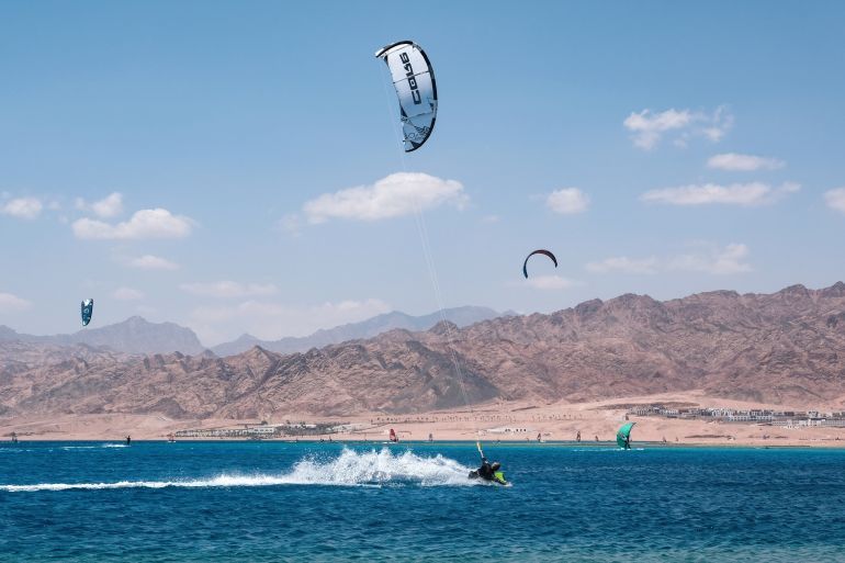 Dahab, Egypt - 5th May, 2023: Activities in the country. A man kiteboarding in the sea on the background of the mountains and blue sky.