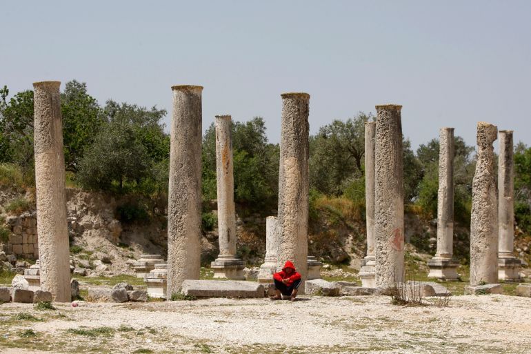 FILE - In this April 6, 2013 file photo, a Palestinian youth sits near the Roman basilica and forum in the village of Sebastia near the West Bank city of Nablus. The ancient town of Sebastia is one of the greatest archaeological sites of the Holy Land. A new study published Monday, June 8, 2015, by the RAND Corp. says that Israelis and Palestinians would gain billions of dollars from peace. The study indicates over the next decade Israelis would gain $120 billion from a peace deal. The Palestinians would gain $50 billion, marking a 36-percent rise in their average per-capita income. (AP Photo/Majdi Mohammed, File)