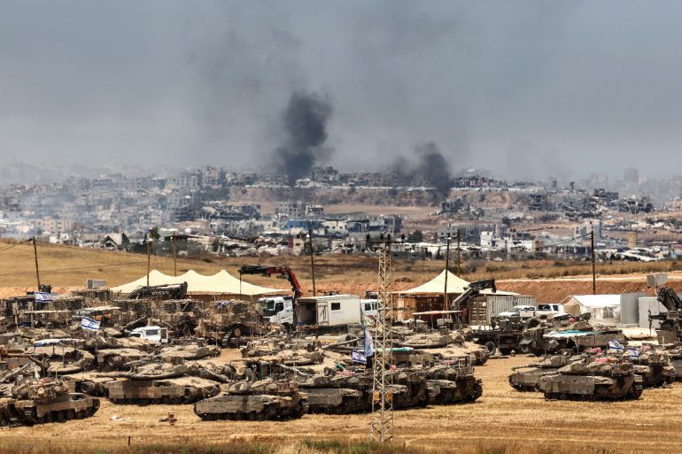 This picture taken from a position in southern Israel on the border with the Gaza Strip shows Israeli tanks and bulldozers deployed as smoke billows over destroyed buildings in Gaza during Israeli bombardment on May 17, 2025.