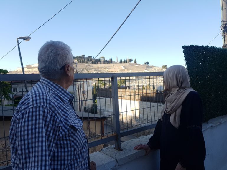 رأس العامود، القدس، الزوجان المقدسيان حسن وهيام الغول يترجعان ذكرياتهما وينظران إلى الجبل الذي يعج بقبور يهودية (الجزيرة نت)