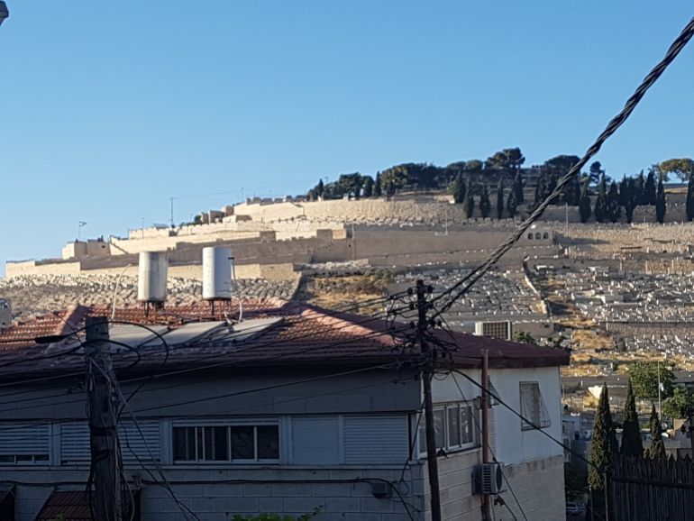 رأس العامود، القدس، المقبرة اليهودية في جبل الزيتون المقابلة لمنزل هيام وحسن الغول ويظهر العلم الإسرائيلي في مؤخرة الصورة (الجزيرة نت).jpg