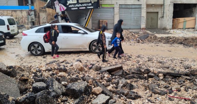 فاطمة محمود الجزيرة نت جنين فلسطين_ طلبة برفقة عائلاتهم يعبرون شارع مدمر بفعل اقتحام الاحتلال لمخيم جنين في وقت سابق