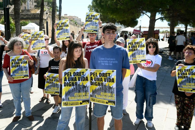 epa12146738 People hold placards reading 'For the right to a dignified life. Stop to Mass Tourism' during a press conference to announce an upcoming protest by 'Less Tourism. More Life' collective against mass tourism and in defense of housing rights, in Palma de Mallorca, Spain's Balearic Island of Mallorca, 31 May 2025. The group calls for rallies under the slogan 'the right to a dignified life and an end to touristification' to be held on 15 June. EPA-EFE/MIQUEL A. BORRAS