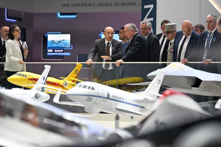 French Prime Minister François Bayrou (C-R) visits the stand of French aircraft manufacturer Dassault Aviation with its CEO Eric Trappier (C-L) during the 55th edition of the International Paris Air Show at the Paris–Le Bourget Airport, in Le Bourget, suburb of Paris on June 16, 2025. (Photo by JEANNE ACCORSINI / POOL / AFP)
