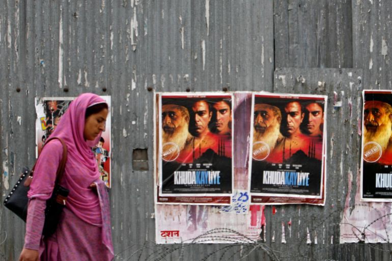 A Kashmiri woman walks past posters of Pakistani movie