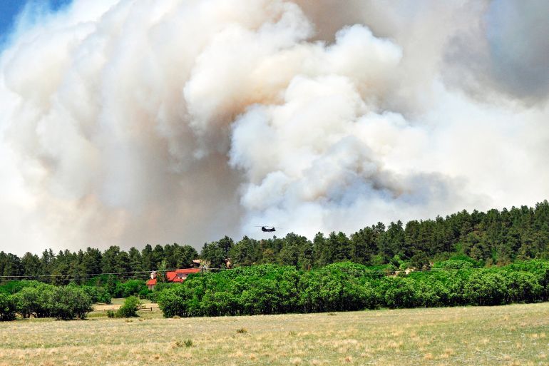BLACK FOREST, CO - JUNE 12: In this handout photo provided by the U.S. Army, Pilots and crewmembers of the United States Army release water onto the burning fires during their bambi bucket mission on June 12, 2013 in Black Forest, Colorado. The fire has burned over 15,000 acres, and has claimed 360 homes, forcing at least 38,000 people to evacuate. Sgt. Jonathan C. Thibault/U.S. Army via Getty Images/AFP (Photo by Handout / GETTY IMAGES NORTH AMERICA / Getty Images via AFP)