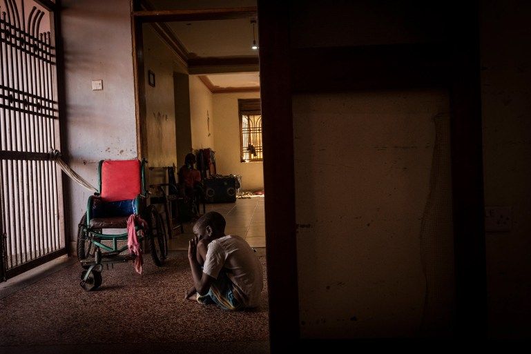 Joseph, 10, sits alone outside the therapy room at the Home of Hope [Christopher Hopkins/Al Jazeera]