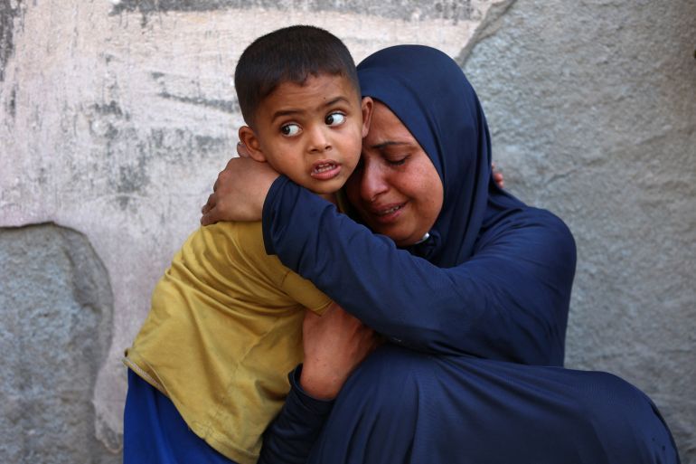 A Palestinian woman mourns near the bodies of loved ones killed during overnight Israeli strikes, on the grounds of Al-Shifa hospital in the central Gaza Strip on June 28, 2025.