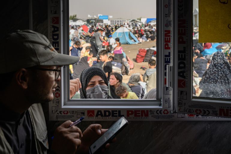 An employee of the NGO World Vision assists a woman at an office where deported Afghans can call their family members, 3 July, Islam Qala, Afghanistan. Photograph: Getty Images