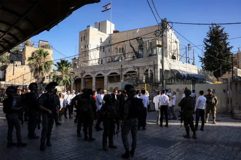 TOPSHOT - Israeli security forces stand guard as Israeli settlers tour in the Palestinian side of the old city and market of Hebron in the occupied West Bank on July 5, 2025. (Photo by HAZEM BADER / AFP)