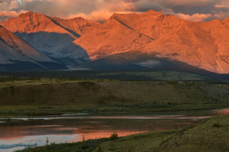 The midnight sun shines on the mountains lining the Wind River in the Peel watershed - stock photo Yukon, Canada