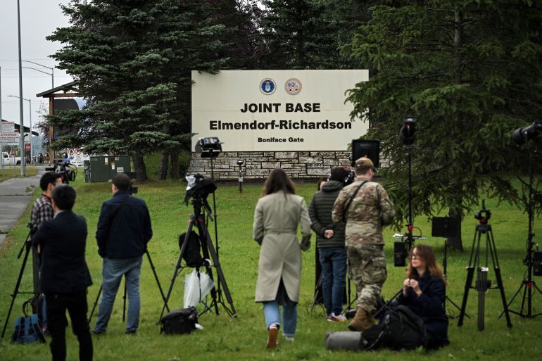 Journalists work near an entrance to Joint Base Elmendorf-Richardson in Anchorage, Alaska, on August 14, 2025, ahead of the August 15 scheduled meeting between US President Donald Trump and Russian President Vladimir Putin.