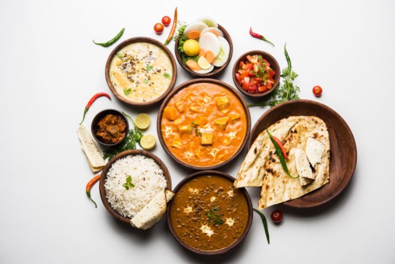 Assorted indian food for lunch or dinner, rice, lentils, paneer butter masala, palak panir, dal makhani, naan, ...
