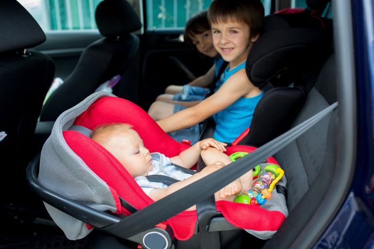 Little baby boy and his older brothers, traveling in car seats, going on a holiday, traveling on the back seat