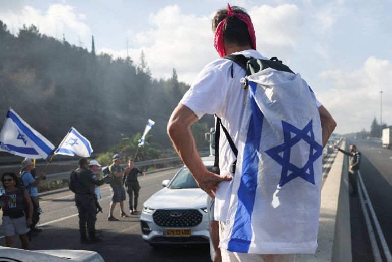 A man looks on as demonstrators block Israel's main highway connecting Jerusalem and Tel Aviv, after families of hostages have called for a nationwide strike to demand the return of all hostages and an end to the war in Gaza, in Latrun Israel August 17,2025 REUTERS/Ronen Zvulun