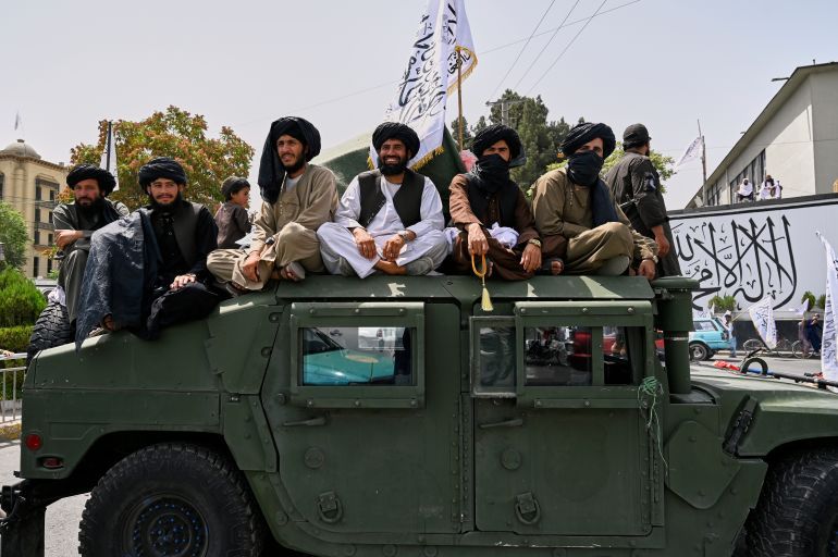 Taliban fighters ride on the roof of a Humvee during celebrations for the fourth anniversary of the U.S. withdrawal and the start of Taliban rule in Kabul, Afghanistan, Friday, Aug. 15, 2025. (AP Photo/Nava Jamshidi)