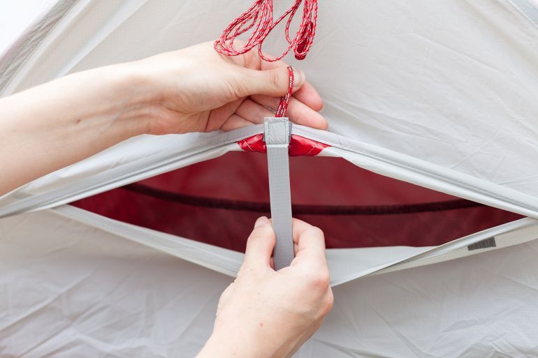 The girl opens a ventilation window in a tourist tent and fixes it with a velcro