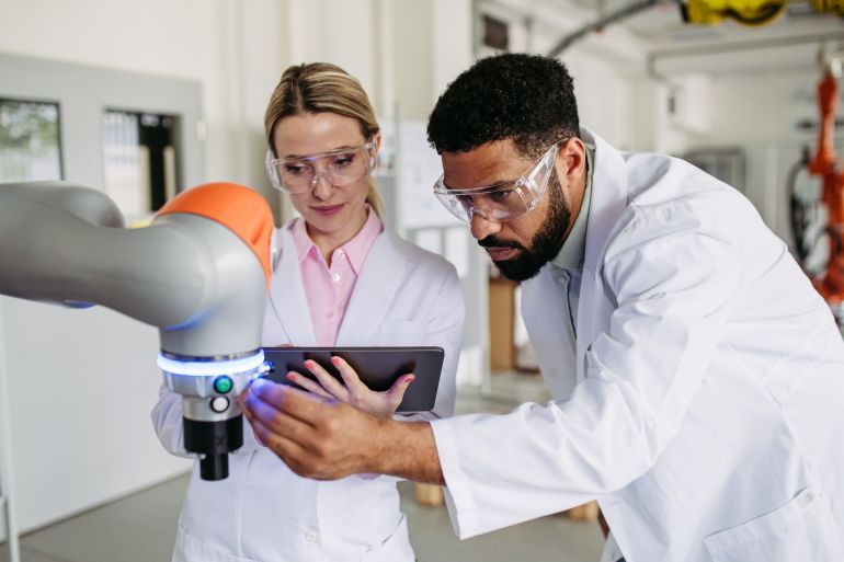Robotic engineer colleagues working on robotic knee replacement surgery project, adjusting robots settings. Concept of robotics, engineering and computer science in healthcare.